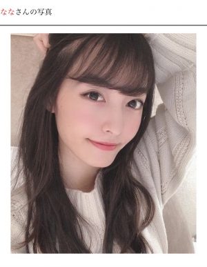 白いニットを着て髪を掻き上げているロングヘアの女性