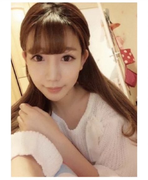 白いニットを着て自撮りをしているロングヘアの女性