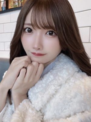 白いもこもこしたトップスを着て、手を顎に当てて甘えん坊ポーズを取ってこちらを見つめている女性。