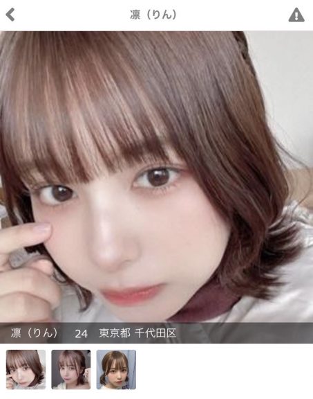 茶髪のボブストレートヘアの女性のドアップ。右手人差し指を頬に当てている。