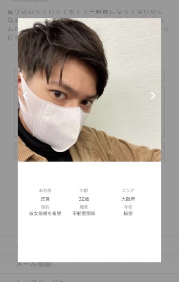 薄茶色いコーデュロイジャケットを羽織って、白いマスクをしてこちらを睨みつけている男性。